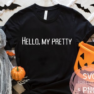 Puede incluir: Camiseta negra con el texto "HELLO, MY PRETTY" en blanco. La camiseta está rodeada de decoraciones de Halloween, incluyendo una calabaza, un esqueleto y murciélagos.