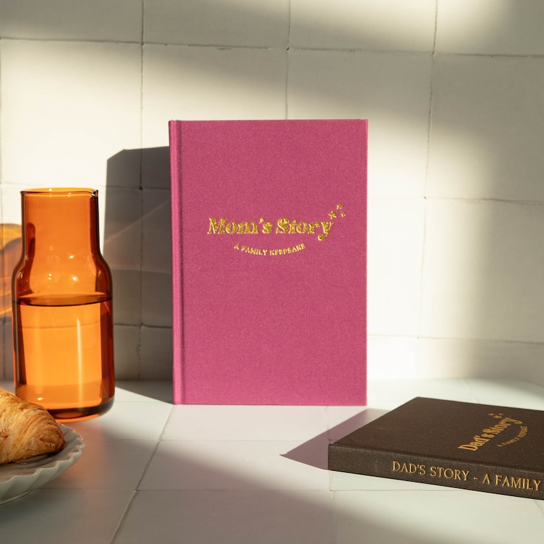 May include: Two pink and brown hardcover journals with gold lettering. The pink journal says "Mom's Story - A Family Keepsake" and the brown journal says "Dad's Story - A Family Keepsake".