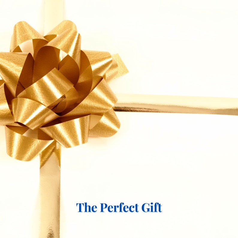 Peut inclure: Un n&oelig;ud dor&eacute; nou&eacute; avec un ruban sur un fond blanc. Le texte "The Perfect Gift" est imprim&eacute; sous le n&oelig;ud.