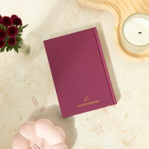 May include: A burgundy hardcover journal with gold stars and the text "Catch Your Dreams" on the front cover.