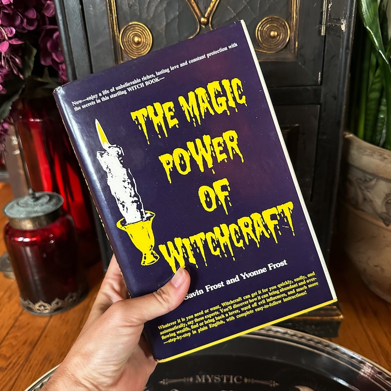 K&ouml;nnte beinhalten: Ein blaues Buch mit dem Titel "The Magic Power of Witchcraft" von Gavin Frost und Yvonne Frost. Der Buchumschlag zeigt einen gelben Kerzenhalter mit einer wei&szlig;en Kerze.