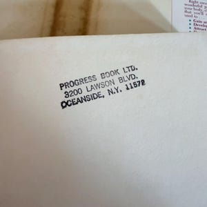 May include: Close-up of a white paper with black text. The text reads "PROGRESS BOOK LTD. 3200 LAWSON BLVD. OCEANSIDE, N.Y. 11572". The paper is slightly wrinkled.