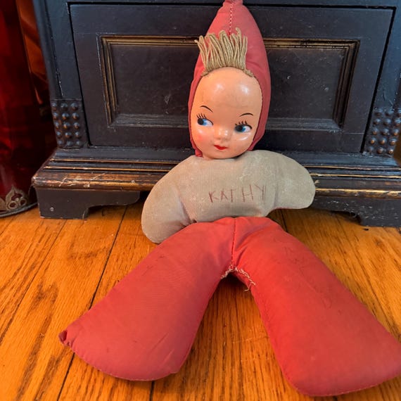 A real 1940s–50s cloth folk-art doll with an original composition face — genuine vintage artifact with that eerie antique-store energy.
