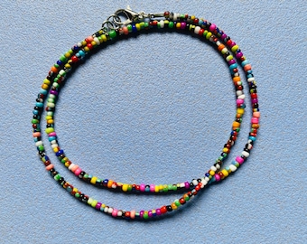 May include: A multi-colored beaded necklace with a silver clasp. The beads are small and round, and they are arranged in a random pattern. The necklace is about 18 inches long.