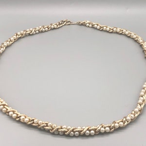 May include: A silver and white pearl necklace with a braided design.
