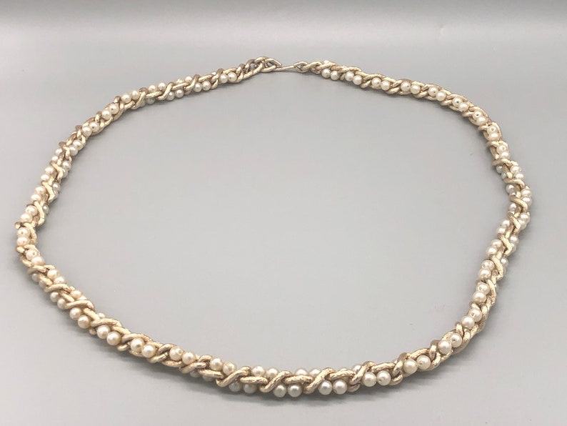May include: A silver and white pearl necklace with a braided design.