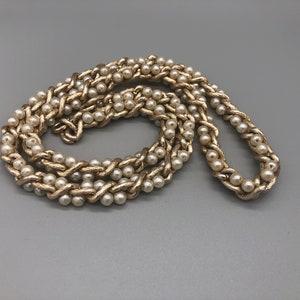 May include: A gold chain necklace with faux pearls woven into the chain.