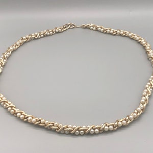 May include: A gold chain necklace with white faux pearls woven into the chain.