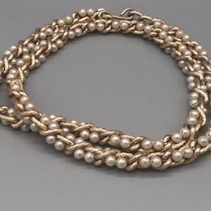 May include: A gold-tone necklace with a braided chain design and faux pearl accents.