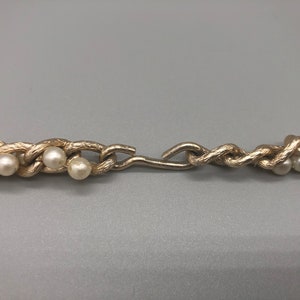 May include: A gold chain necklace with faux pearls. The chain is twisted and has a clasp.