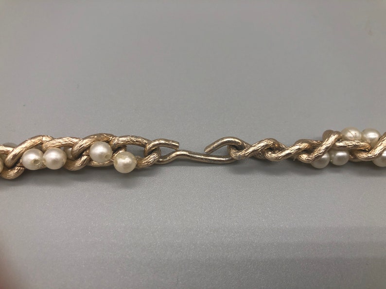 May include: A gold chain necklace with faux pearls. The chain is twisted and has a clasp.