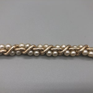 May include: A gold chain necklace with faux pearls woven into the chain.