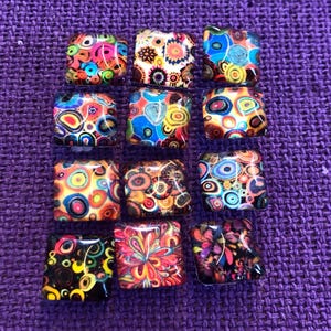 May include: A collection of 12 colourful square tiles with abstract patterns. The tiles are made of glass and have a glossy finish. The patterns are made up of circles, swirls, and other geometric shapes. The colours are bright and vibrant, including red, orange, yellow, green, blue, and purple.