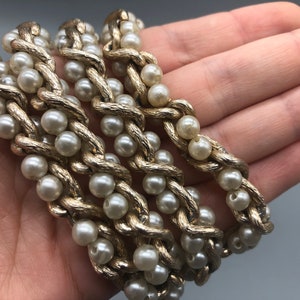 May include: A gold chain necklace with faux pearls. The chain is twisted and the pearls are evenly spaced.