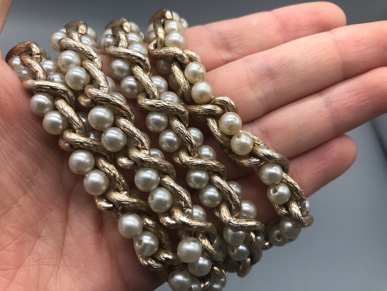 May include: A gold chain necklace with faux pearls. The chain is twisted and the pearls are evenly spaced.