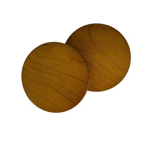 May include: Two round wooden coasters in a light brown color. The coasters are made of wood with a natural grain pattern.