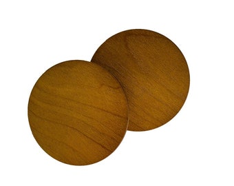 May include: Two round wooden coasters in a light brown color. The coasters are made of wood with a natural grain pattern.