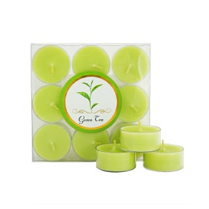 Puede incluir: Un paquete de 12 velas de té verde perfumadas. Las velas están en un recipiente de plástico transparente con una etiqueta que dice "Green Tea". También hay cuatro velas fuera del recipiente.