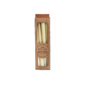 Op de afbeelding: Een doos met 100% bijenwaskaarsen, met het opschrift "100% Beeswax Tapers, Bougies Effil&eacute;es, 100% cire d'abeille". De doos bevat zes witte kaarsen, elk 17 cm lang.