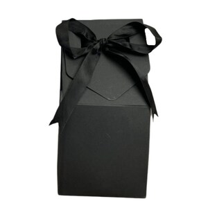 May include: A black gift box with a black satin ribbon tied in a bow on top.
