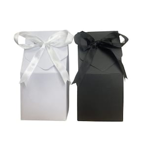 May include: Two gift boxes, one white with a white satin ribbon and one black with a black satin ribbon.