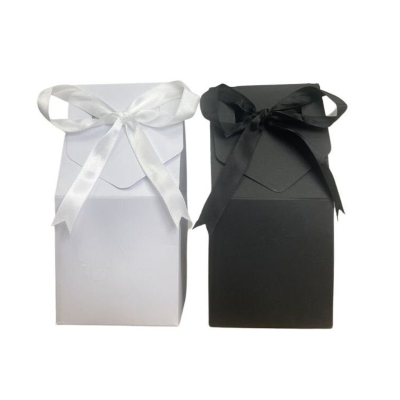 May include: Two gift boxes, one white with a white satin ribbon and one black with a black satin ribbon.