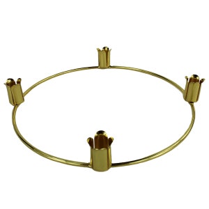 May include: Gold metal candle ring with four candle holders. The ring is circular and the holders are shaped like a flower.