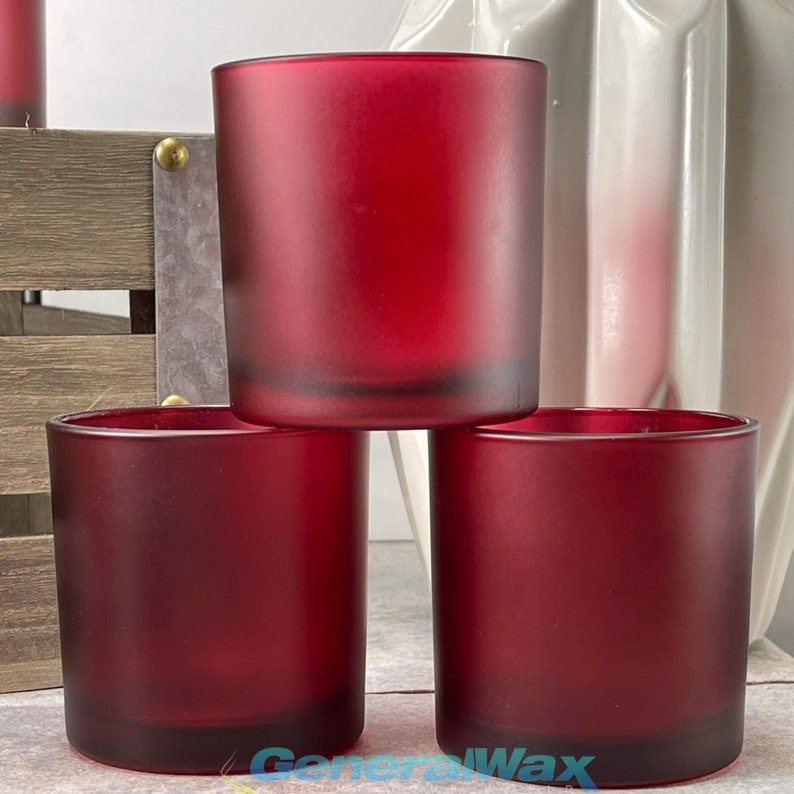 May include: Three red frosted glass candle jars. The jars are stacked on top of each other.