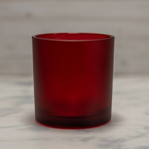 May include: A red glass candle jar with a frosted finish. The jar is empty and ready to be filled with wax and a wick.