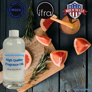 Puede incluir: Una botella de vidrio transparente con una etiqueta blanca que dice "GeneralWax High Quality Fragrance Oil 16 oz. (473.176 ml)". La botella está sobre una tabla de cortar de madera con rodajas de pomelo y ramitas de romero. El fondo es una superficie de madera azul oscuro. La imagen también incluye un pequeño vaso de líquido rosa con una rodaja de pomelo y una ramita de romero dentro. La imagen también incluye un círculo negro con la palabra "ifra" en texto blanco y un escudo rojo, blanco y azul con el texto "MADE IN THE U.S.A."
