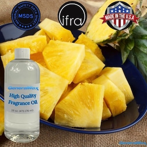 Könnte beinhalten: Eine durchsichtige Glasflasche mit einem weißen Etikett, auf dem "GeneralWax Hochwertiges Duftöl 16 oz (473,176 ml)" steht. Die Flasche steht auf einem blauen Teller mit Ananasscheiben.