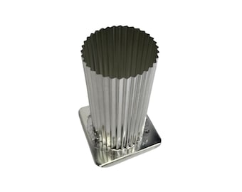 May include: A silver-colored, fluted metal candle mold with a square base. The mold has a cylindrical shape with vertical ridges and a scalloped top edge. The base is also silver and square, providing stability for the mold.