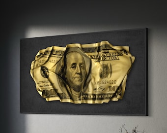 May include: A framed artwork featuring a gold-colored, crumpled $100 bill. The artwork is set against a dark background, with the portrait of Benjamin Franklin visible. The piece is displayed in a modern office setting.