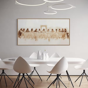 May include: A sepia-toned print of The Last Supper in a wooden frame hangs above a white oval dining table. White chairs with black legs surround the table. White vases and a small flower arrangement are on the table. Modern lighting fixtures are suspended from the ceiling.