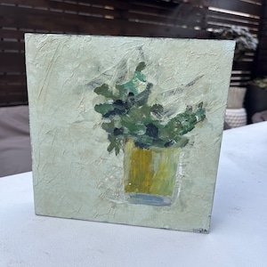 May include: A painting of a green plant in a yellow glass vase on a textured white background.