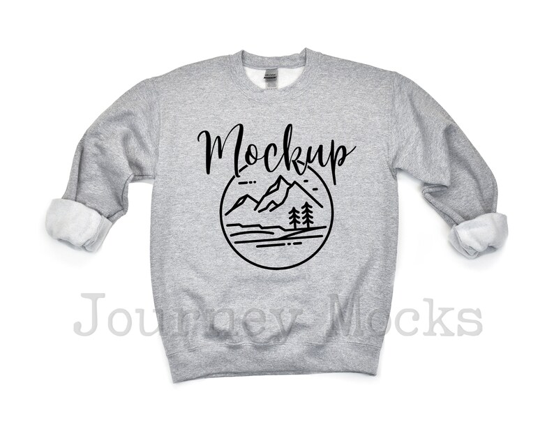 May include: Gray sweatshirt with a black mountain and tree graphic and the word "Mockup" in a handwritten font.