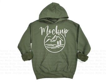 May include: A green hooded sweatshirt with a white graphic of mountains and trees in a circle. The text "Mockup" is written above the graphic.