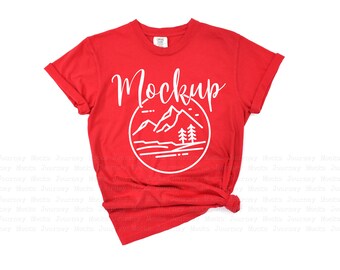 May include: Red t-shirt with a white mountain and trees graphic and the word "Mockup" in white text.
