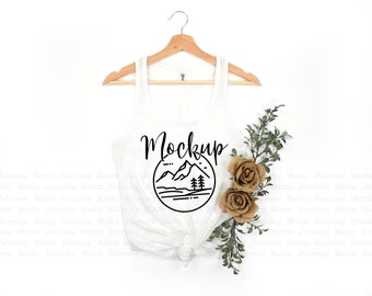 Op de afbeelding: Witte tanktop mockup met een zwarte afbeelding van een bergketen en bomen in een cirkel. De tekst "Mockup" staat boven de afbeelding.