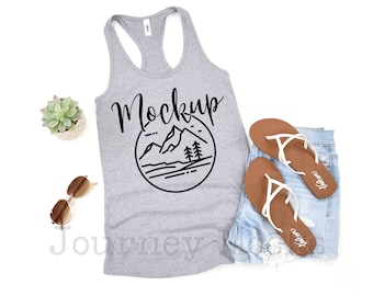 May include: Gray tank top with a black graphic of mountains and trees in a circle with the word "Mockup" written in cursive above the graphic.