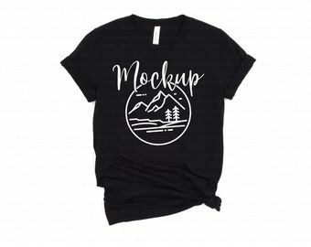 May include: Black t-shirt with a white graphic of mountains and trees in a circle. The text "Mockup" is above the graphic.