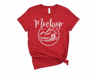 May include: Red t-shirt with a white graphic of mountains, a lake, and trees. The text "Mockup" is above the graphic.