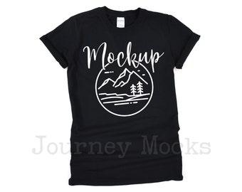 May include: Black t-shirt with a white graphic of mountains, trees, and a lake. The text "Mockup" is written in a cursive font above the graphic.
