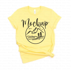 May include: A yellow t-shirt with a black graphic of mountains and trees. The text "Mockup" is written above the graphic.