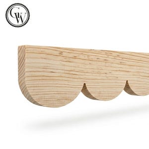 May include: A light-colored wooden shelf with a scalloped edge. The shelf is made of natural wood and has a smooth finish. The design features three curved cutouts along the bottom edge.