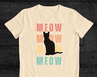 May include: A beige t-shirt with a black cat silhouette and the word "MEOW" repeated four times in a retro style font. The word "MEOW" is in different colors: red, orange, yellow, and blue.