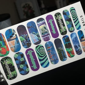 May include: A sheet of nail decals featuring various Goosebumps-themed illustrations, including green slime, horror landscapes, and the Goosebumps logo in purple and green. The white backing sheet includes the text @BLU_X_NAILS printed vertically.