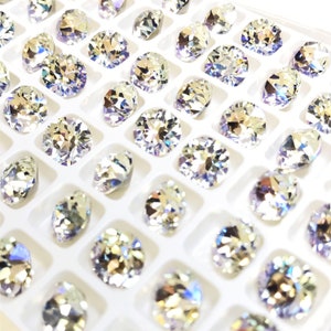 May include: A white plastic tray filled with clear round rhinestones. The rhinestones are arranged in rows and columns.