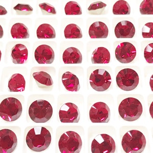 May include: A sheet of clear plastic with small, round, red rhinestones arranged in a grid pattern. The rhinestones are all the same size and shape.