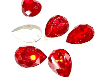 May include: Six red pear-shaped crystal rhinestones on a white background.